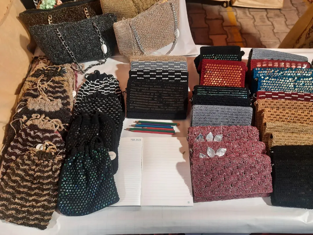 About twenty crochet clutches laid out in rows, every one a different colour and stitch.