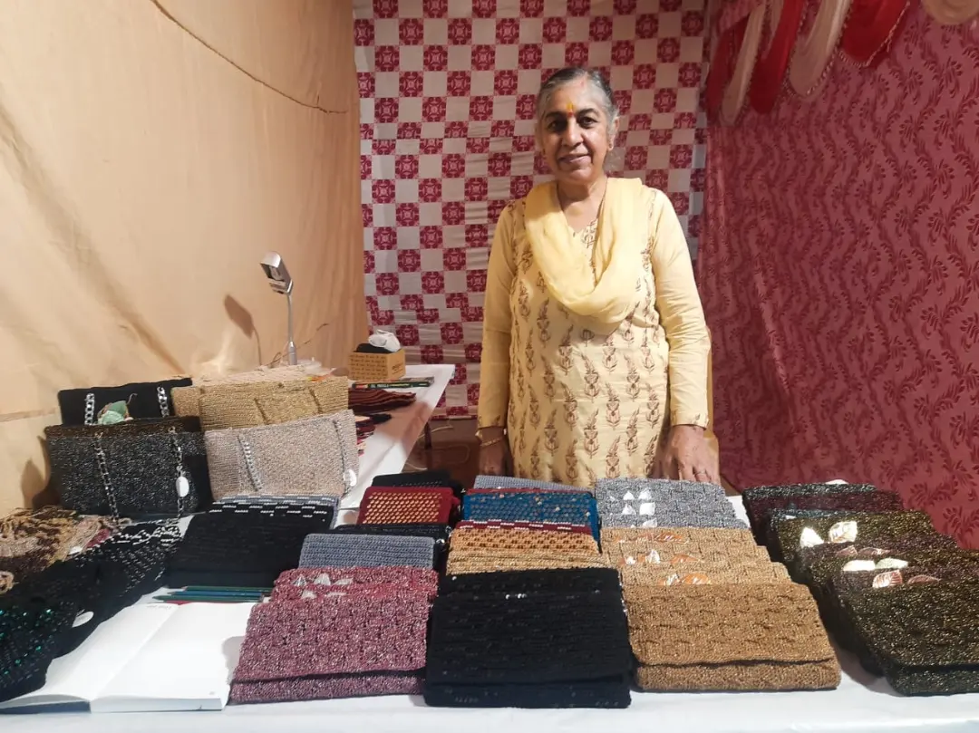 Shikha behind her exhibition table with rows of her crochet clutches laid out.