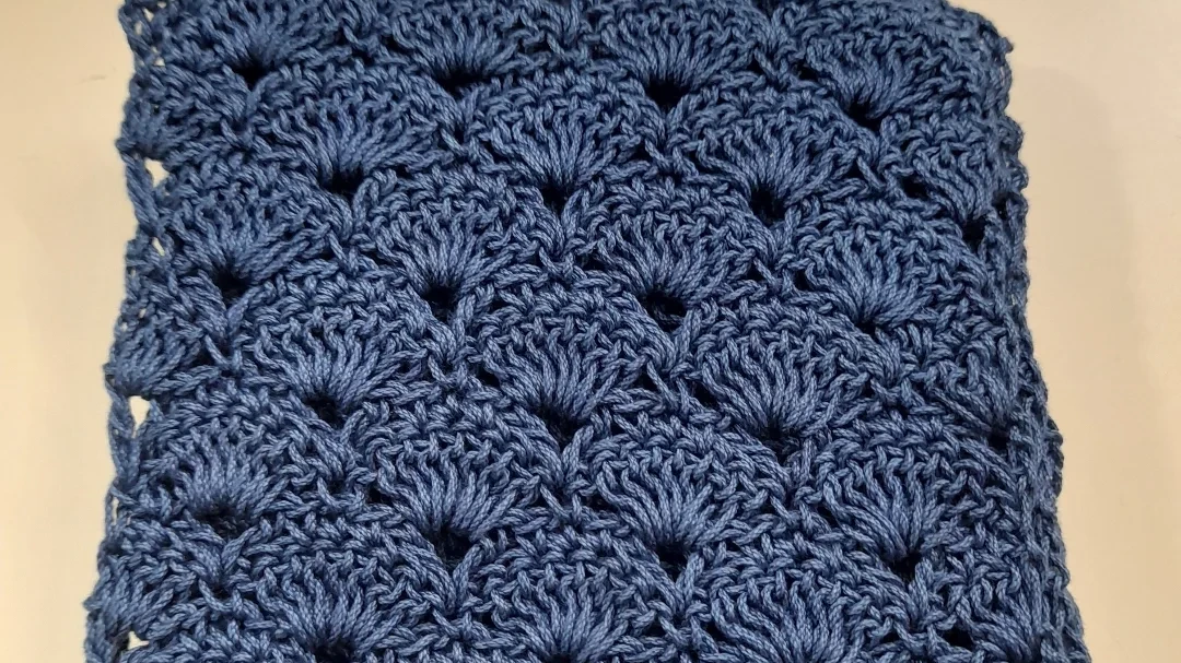 A close view of blue shell stitch, each fan of stitches overlapping the row below.