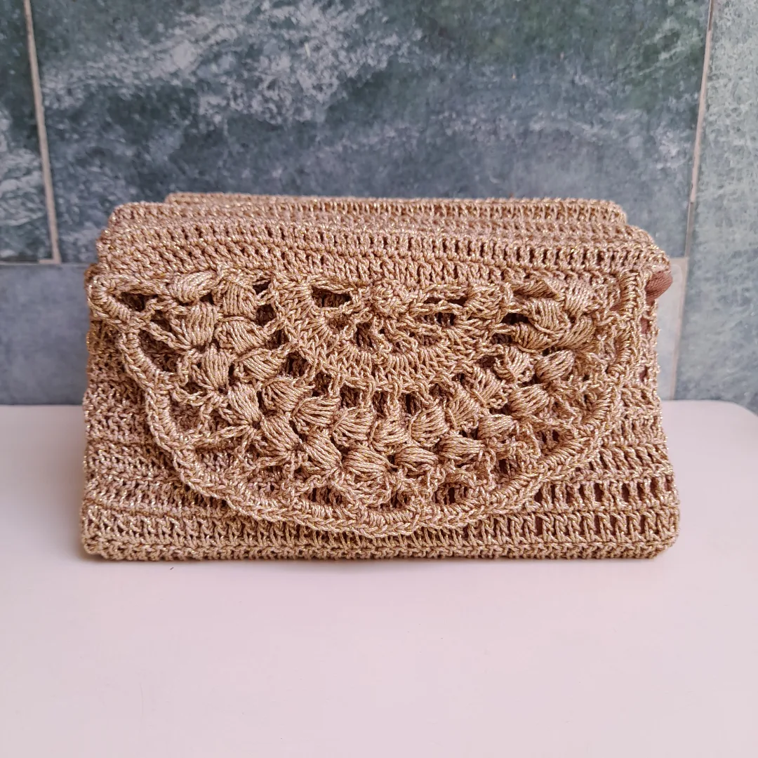 A tan crochet clutch with a scalloped lace flap.