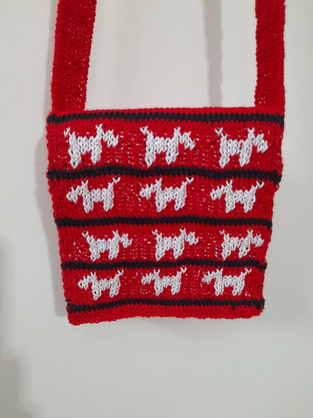 A crochet sling bag with a small dog motif.