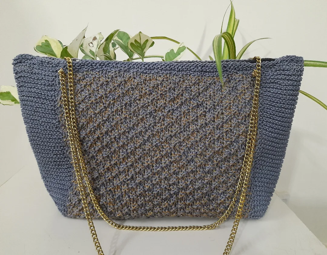 A blue crochet tote with a gold chain strap.