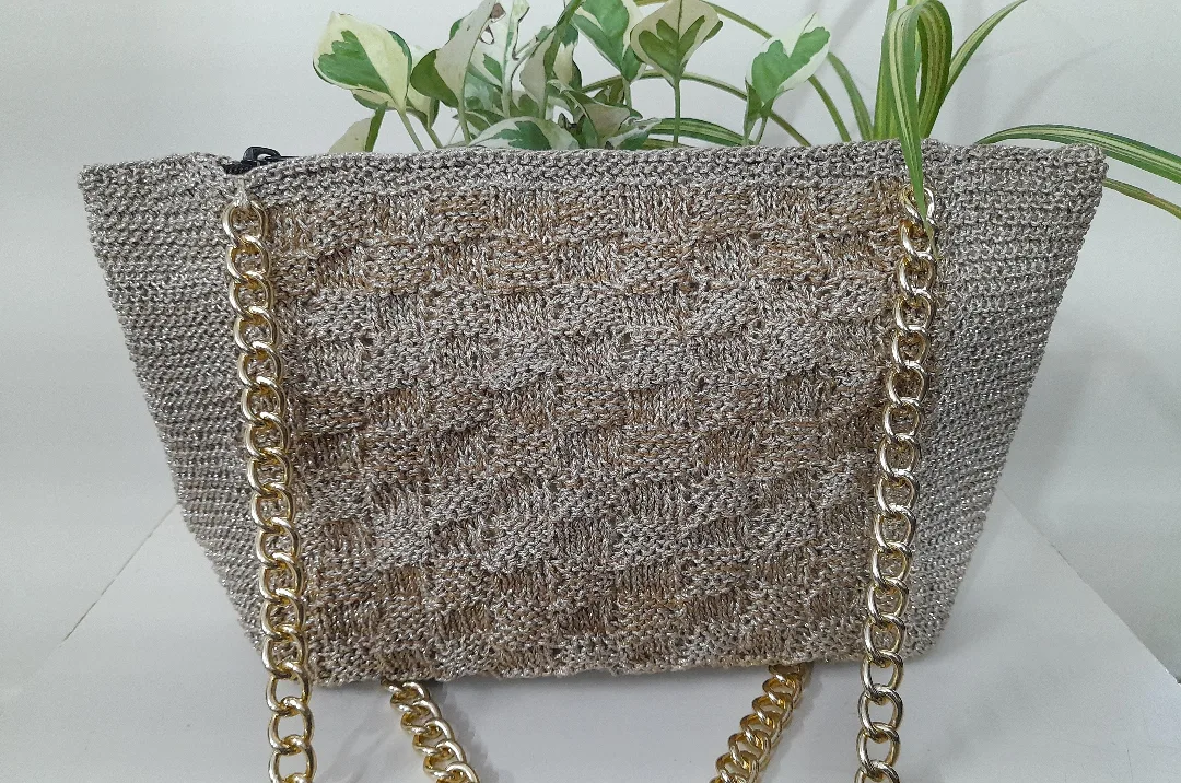 A crochet tote with a silver chain strap.
