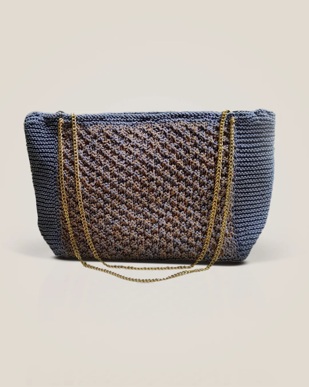 A slate-blue crochet tote with a textured copper-and-blue centre panel and a gold chain strap.