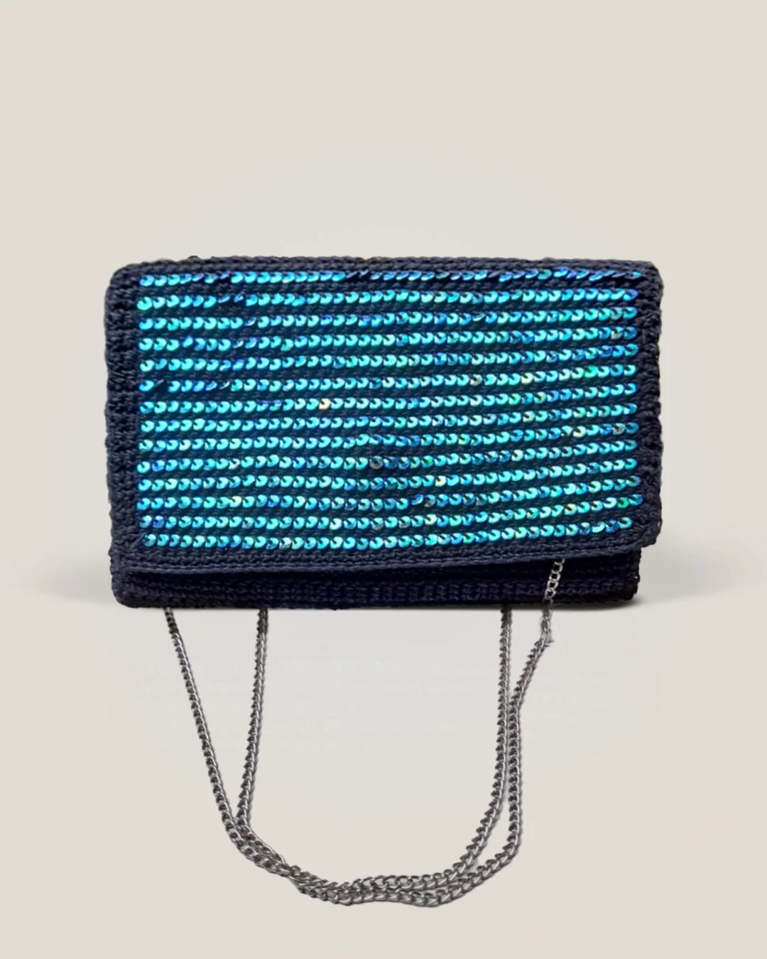 A navy crochet clutch with a fold-over flap covered in rows of peacock-blue sequins, on a silver chain.