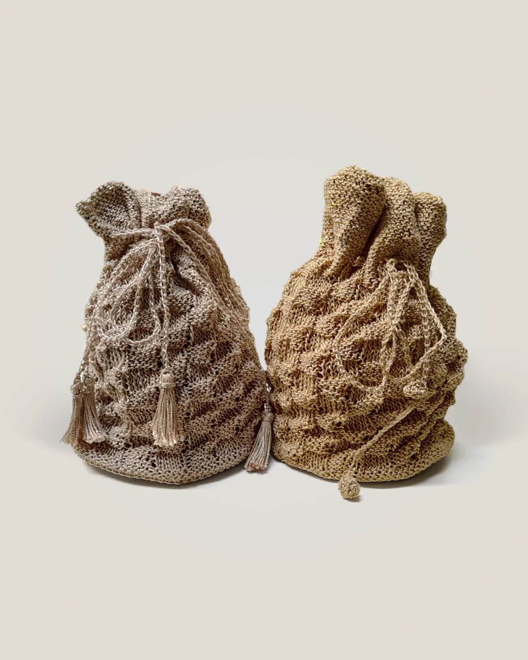 Two drawstring potli bags in champagne and gold, both with a raised block texture, one with tassels.