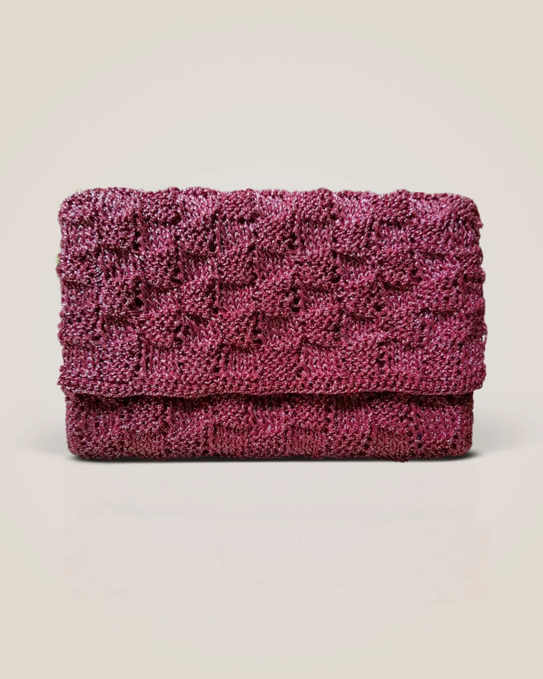 A raspberry crochet clutch with a fold-over flap and a raised block texture with a soft sheen.