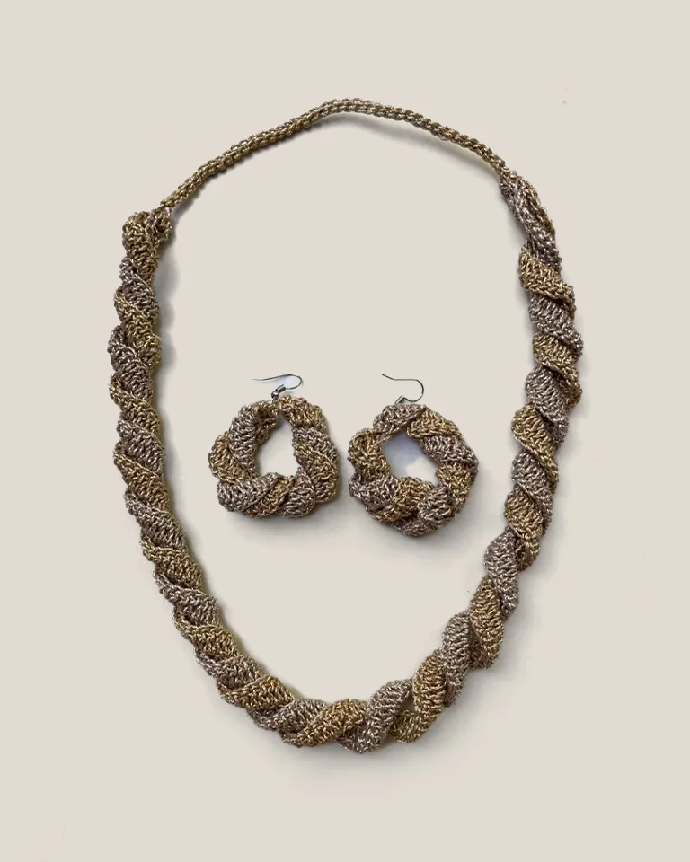 A twisted rope necklace in gold and champagne crochet, with a pair of matching round earrings.