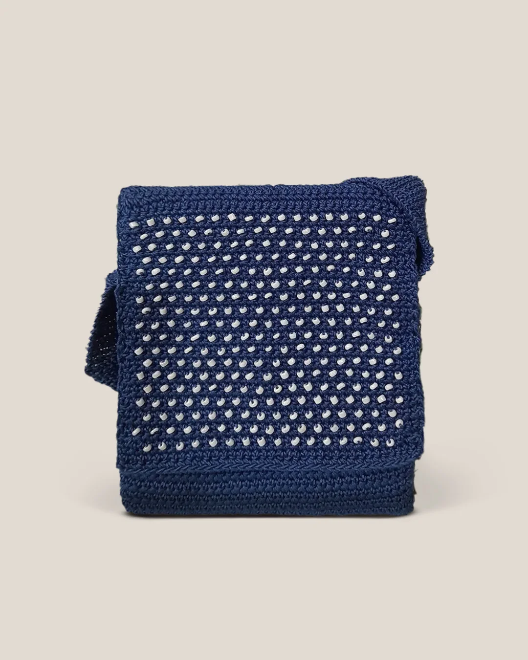A navy crochet sling bag with a fold-over flap set with rows of small white beads.